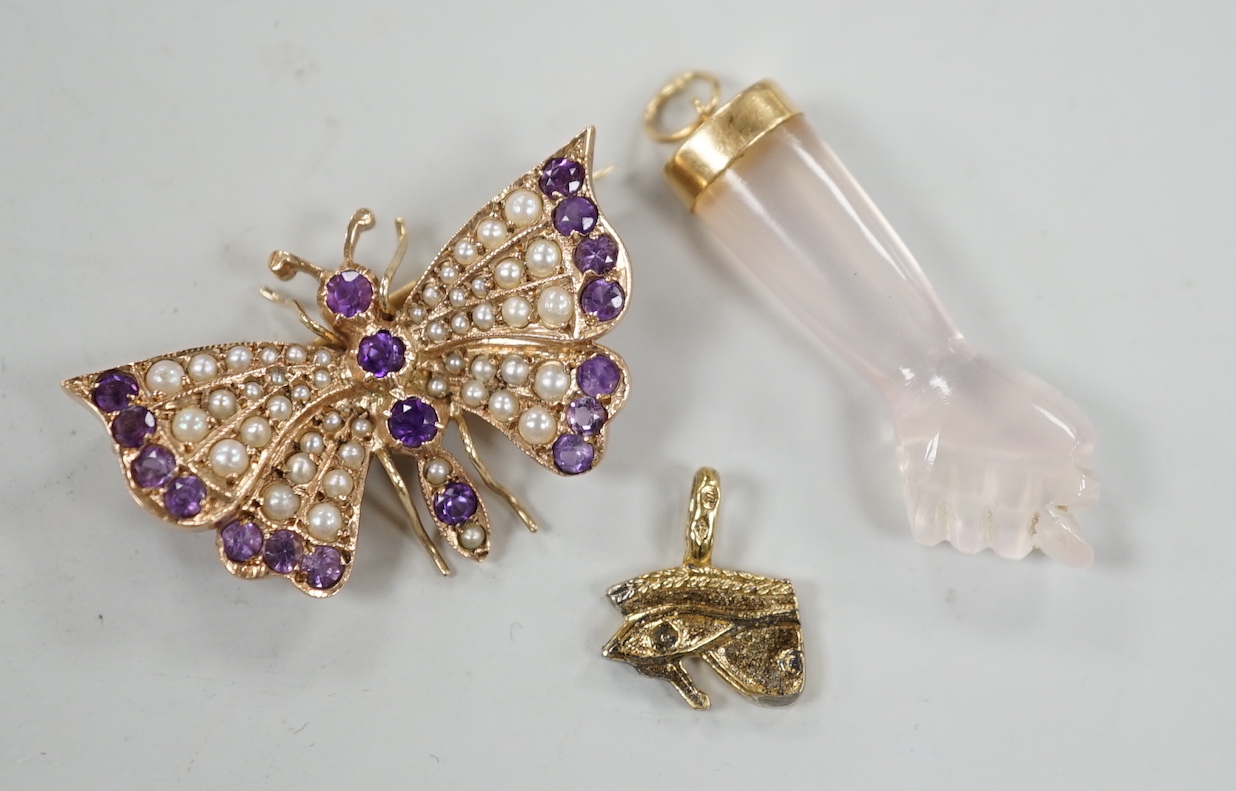 A modern 9ct gold, amethyst and seed pearl cluster set butterfly brooch, width 32mm, together with two charms including arm and fist.
